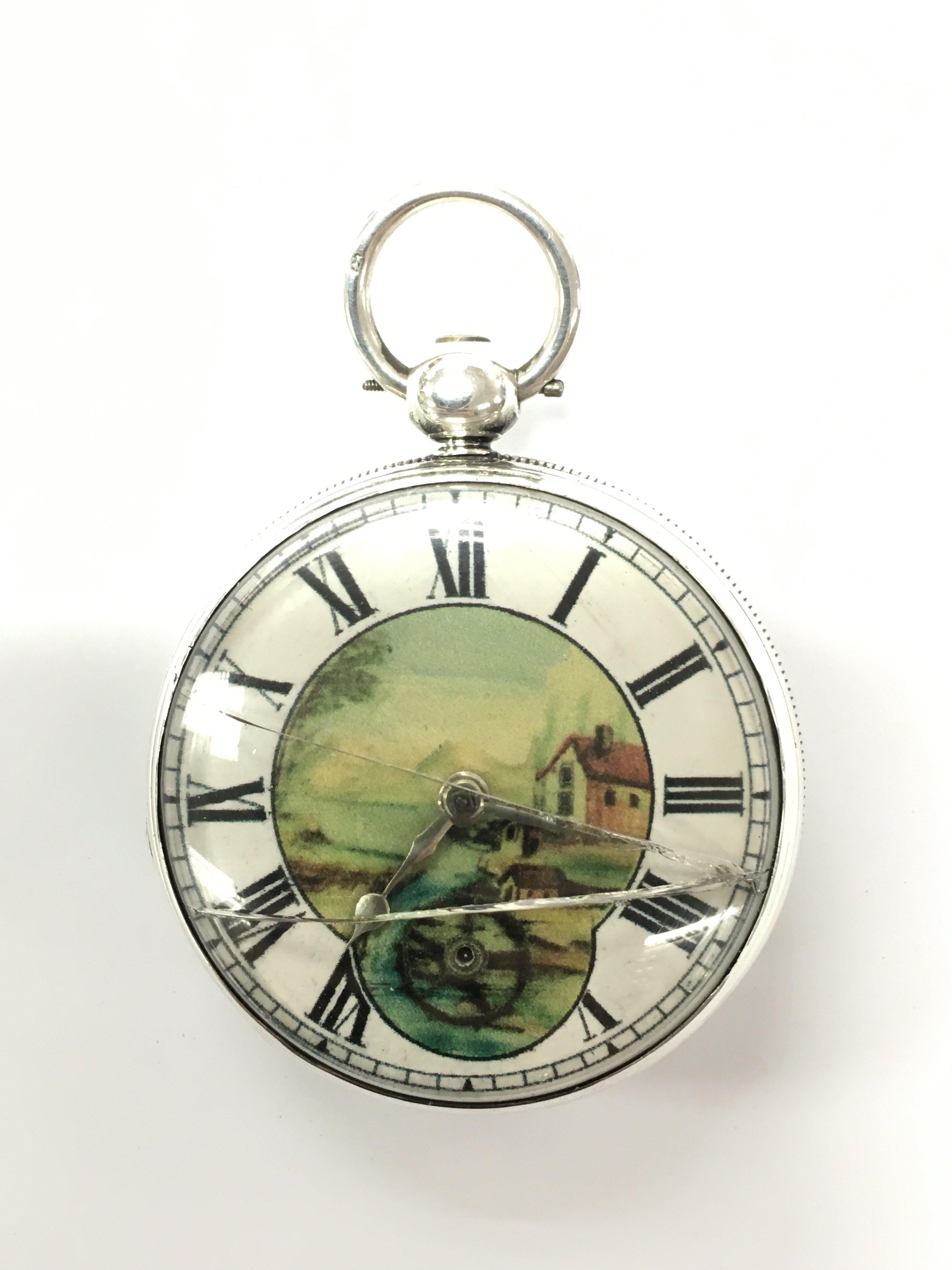 A silver cased pocket watch, the dial printed with a pastoral scene surrounded by Roman numerals.