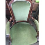 A Victorian walnut open armchair with green upholstery on turned and fluted legs