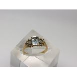 An 18ct gold ring set with a square cut aquamarine flanked by smaller stones