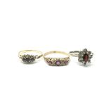 A collection of three 9ct gold rings, including one white gold set with diamonds and a garnet and