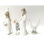 Three Lladro ornaments, two depicting youthful figures, the third being a swan.