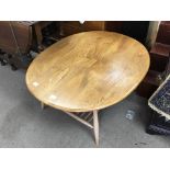 A blonde Ercol Occasional table the splayed legs united by an open magazine rack 100x83cm.