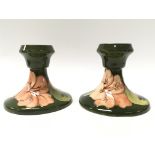 A pair of green Moorcroft candlesticks decorated with hibiscus flowers.