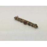 A 9ct gold bar brooch set with a central red stone, approx 1.7g - NO RESERVE