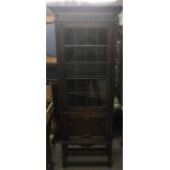 An oak display cabinet with glass lead door sat above a small cupboard. Measures approx 70cm wide