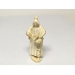 A Continental late 19th Century Carved ivory figure of a lady in traditional dress holding a basket.