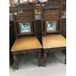 A pair of Edwardian oak hall chairs inset with tiles Ivanhoe and Nigel and King James.