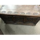 A oak blanket box with carved panel front