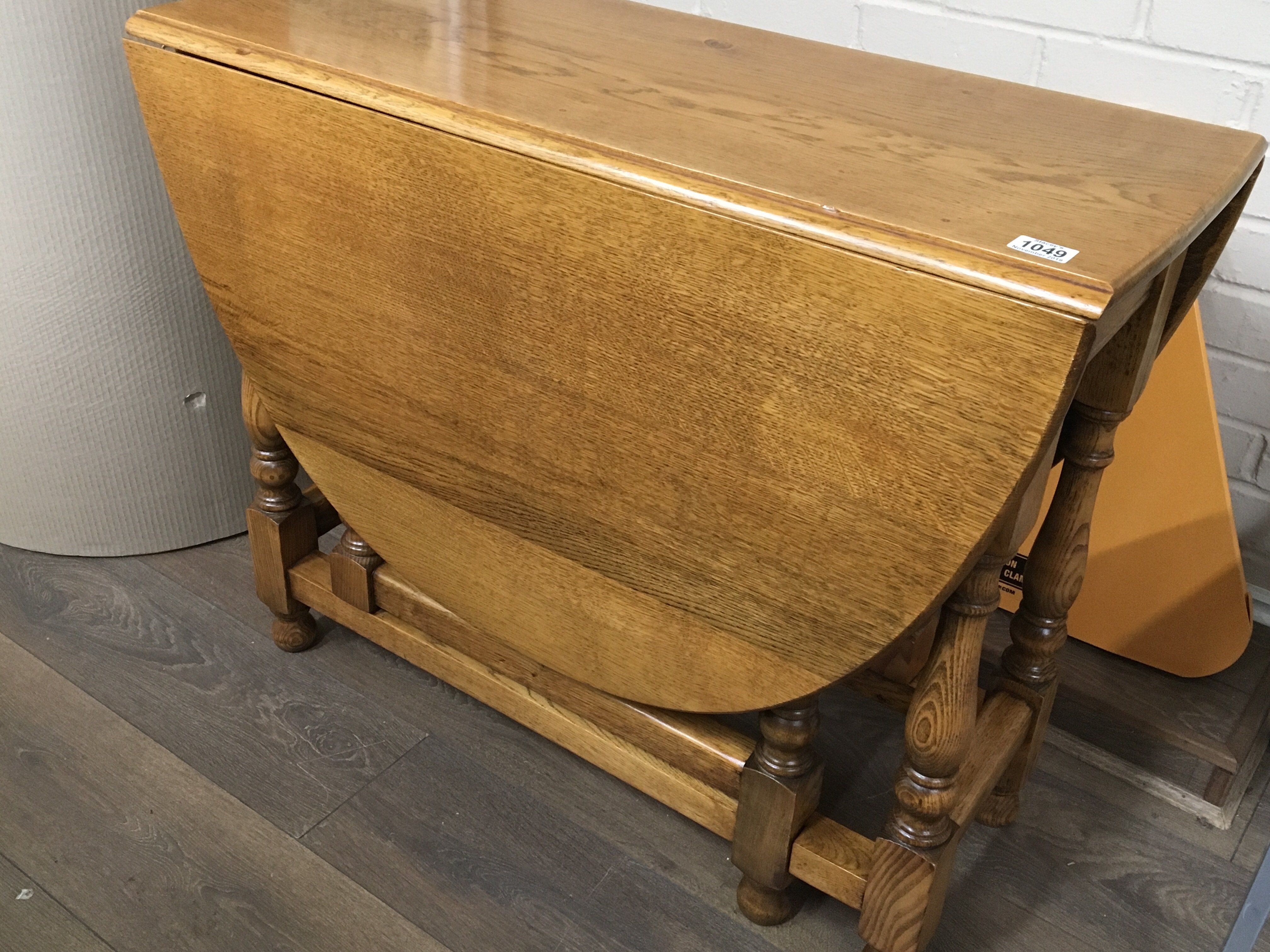 A solid light oak drop leaf table the twin flap top on turned legs.