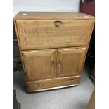 An Ercol type (no makers label) cabinet with a hinged front above cupboard and a drawer.