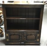 A small oak bookcase with cupboard base and a wicker, glass top bedside cabinet.Bookcase approx
