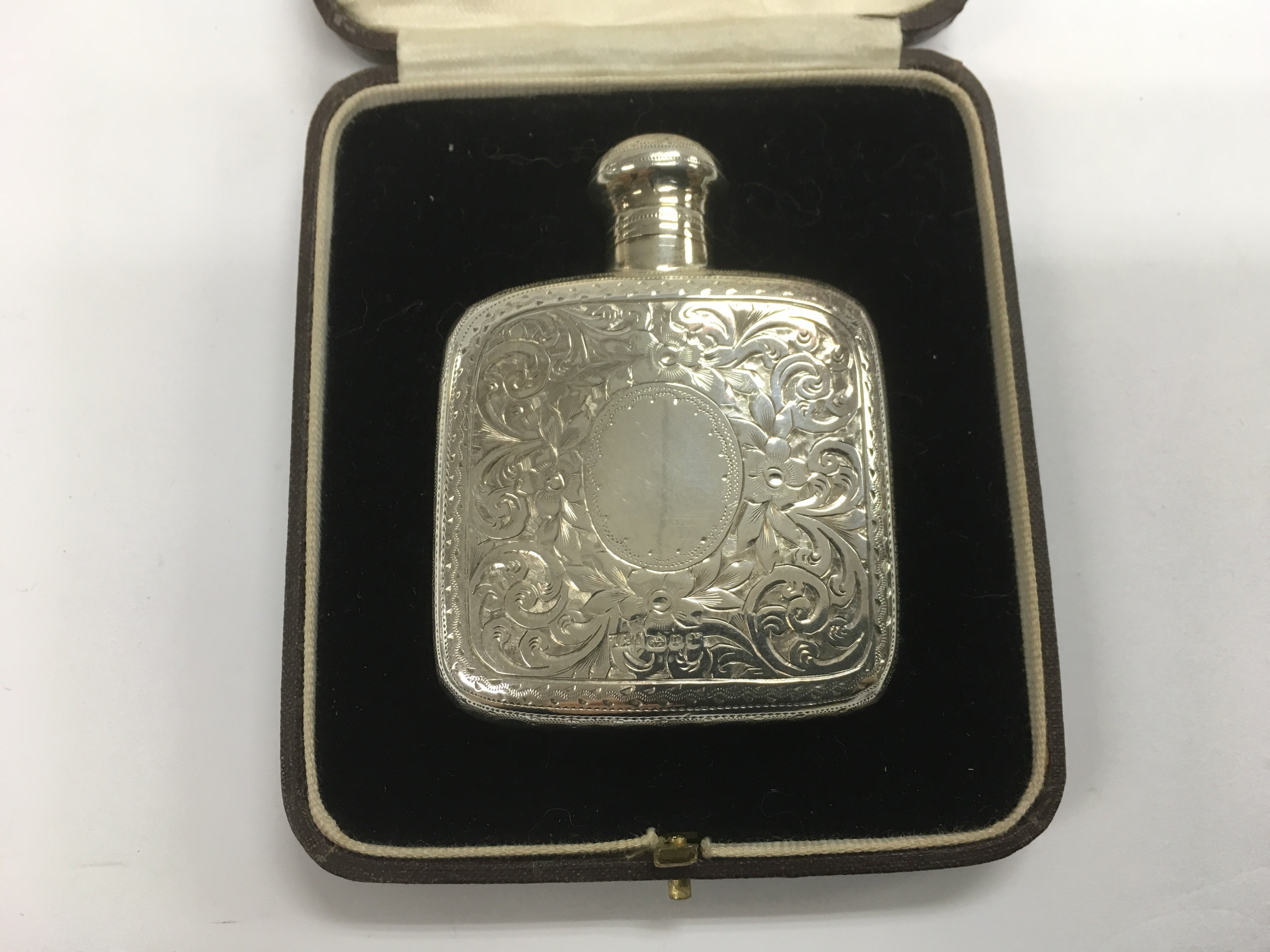 A cased silver perfume bottle with engraved scroll