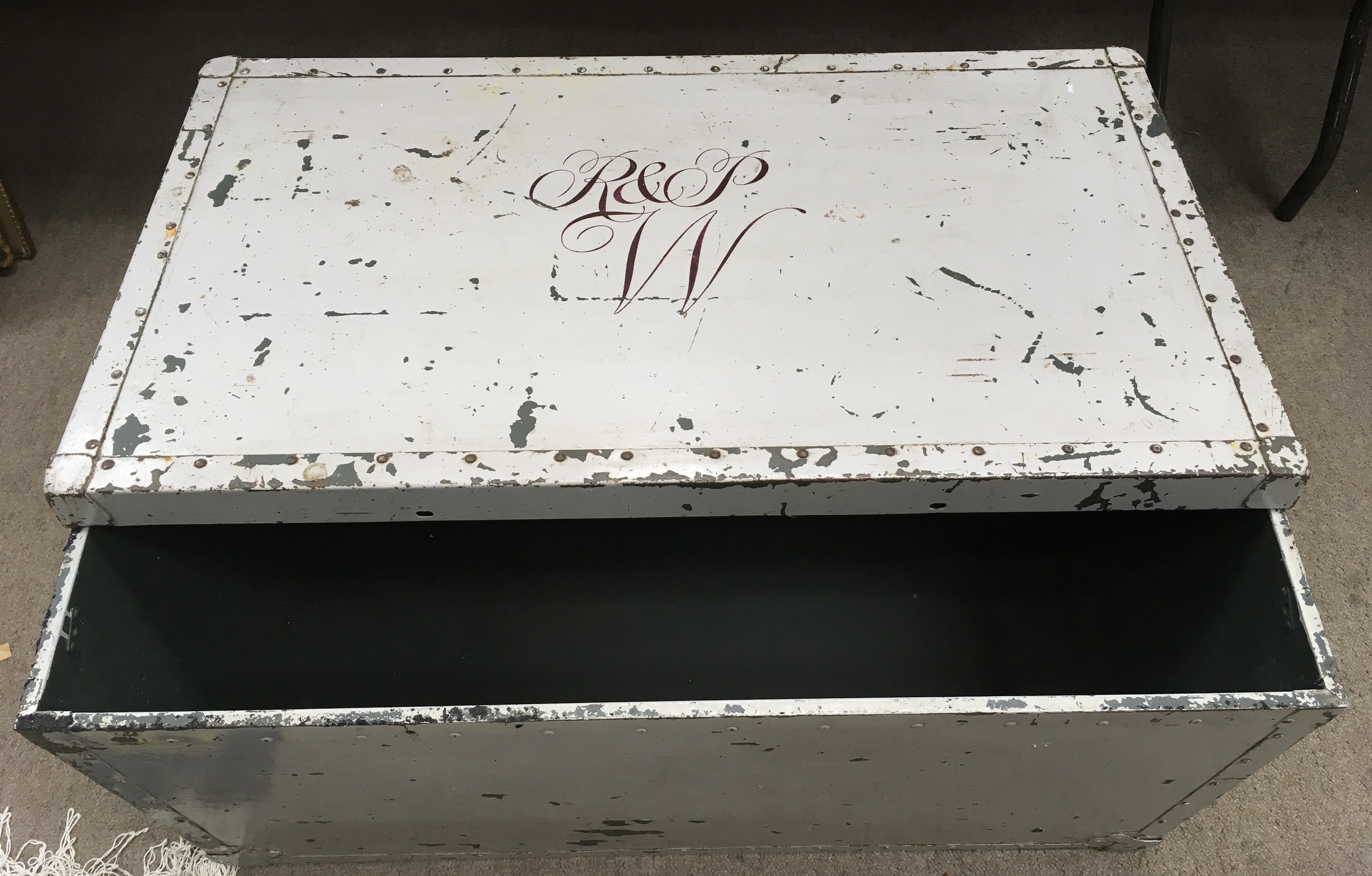 A vintage metal trunk with painted monogram to lid