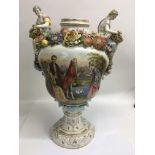 A large Continental vase on stand decorated with figures and encrusted with flowers (missing lid),