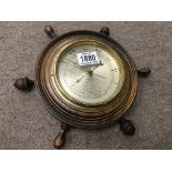 A small barometer in the shape of a ships wheel
