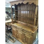 A pine dresser with a raised back and pillar supports above drawers and cupboards 137x48cm