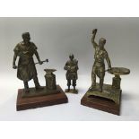 A group of three brass figures to include two black smithing scenes, and an expeditionary. Height