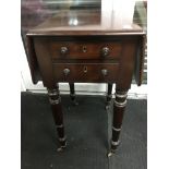 A Victorian mahogany side table the twin flap top above turned legs on brass caps and casters .