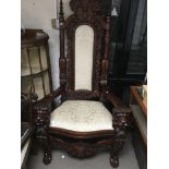A large and ornate chair the open arms in the form of lion heads with upholstered back and seat on