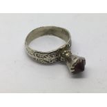 A bezal white metal ring, possibly 17th Century, set with a red stone, approx size Q.