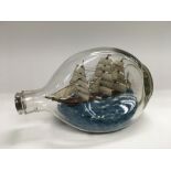 A glass ship in a bottle, approx length 20cm.