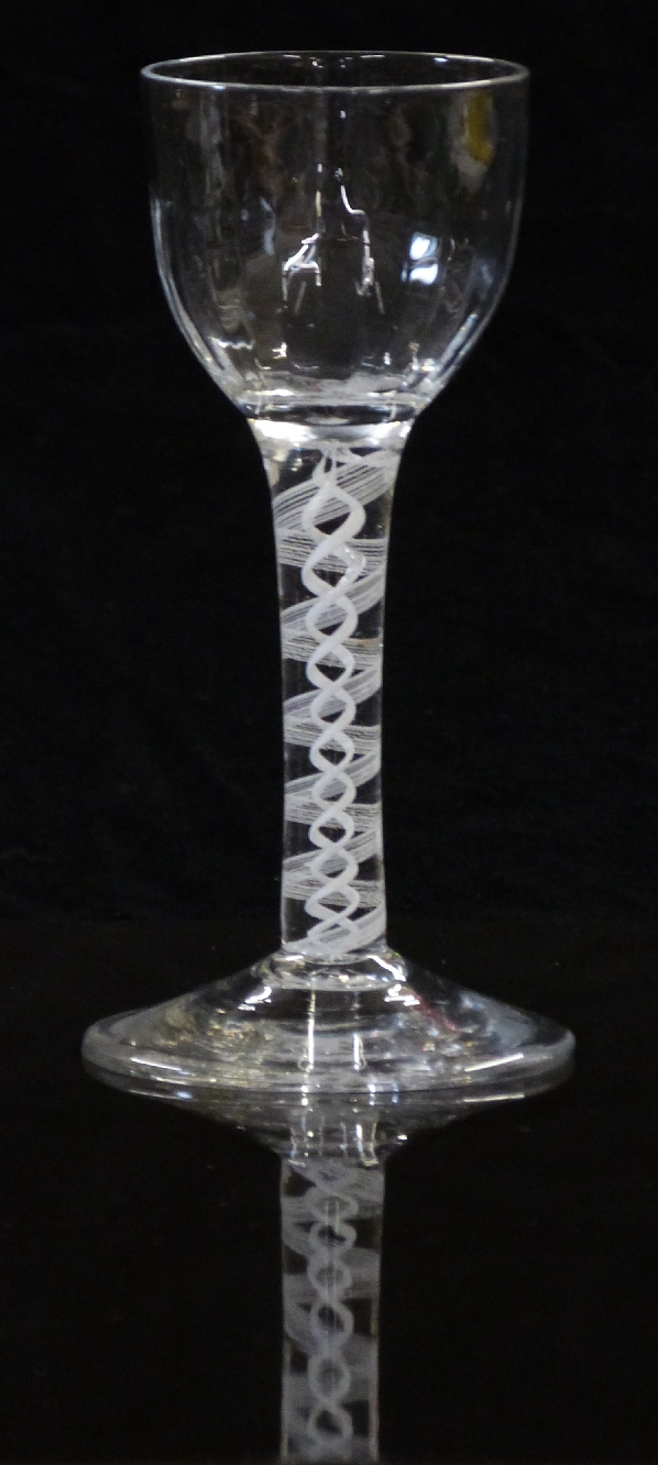 An 18thC clear drinking glass with opaque double twist stem and faceted ogee shaped bowl raised on