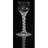 An 18thC clear drinking glass with opaque double twist stem and faceted ogee shaped bowl raised on