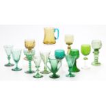 Fourteen coloured drinking glasses including seven German, Dutch or similar green and amber