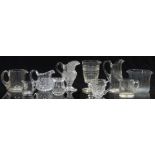 Ten various clear glass jugs and measures most with cut decoration, largest 15.5cm tall.