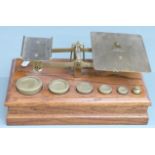 Victorian brass postage scales on oak base with weights from 8oz to 1/2oz, width 29cm