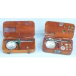 Two wooden cased sets of diamond or similar travelling scales. Width of larger case 12cm