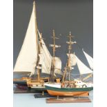 Three wooden model ships comprising a sailing yacht, galleon and a trawler, all on wooden stands,