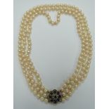 A three strand cultured pearl necklace with a 9ct white gold clasp set with nine round cut