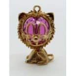 A 9ct gold charm/ pendant in the form of a cat with a pink paste bead to the head, 7.5g