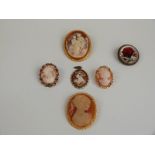 Two cameo brooches, a reverse painted glass brooch and three other brooches
