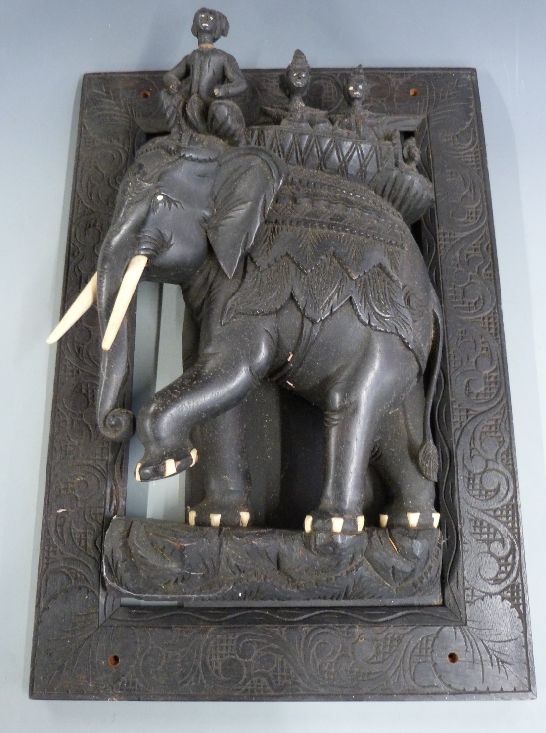 A heavily carved Indian or similar wall plaque featuring four figures atop an elephant