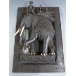 A heavily carved Indian or similar wall plaque featuring four figures atop an elephant