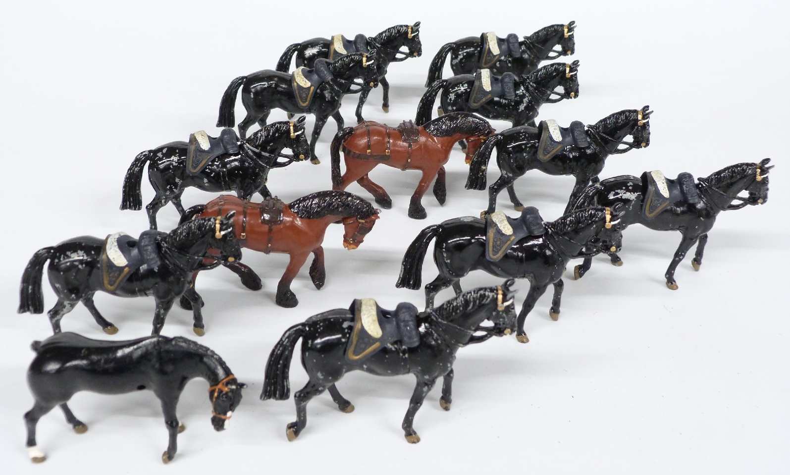 Thirteen Britains and similar diecast model horses with military saddles, each 6.5cm tall