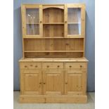 Pine dresser with shelves flanked by two glazed cupboard to top, the base fitted with three