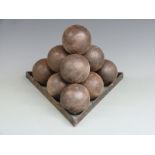 Ten cast iron cannon balls on a cast iron monkey, each approximately 10cm in diameter