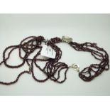 Two single strand garnet necklaces and a three strand garnet example