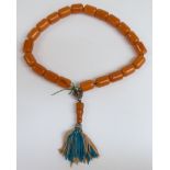 An amber prayer bead necklace of 21 cylindrical beads, each 21.5x15.6mm, with white metal mounts,