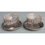 Pair of George V hallmarked silver salts with clear cut glass liners raised on three legs with