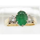 An 18ct gold ring set with an oval cut emerald of approximately 1ct and two diamonds, each