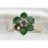 A 9ct white gold ring set with a diamond and emeralds, 2.6g, size N