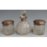 Three hallmarked silver topped cut glass dressing table pots and bottles comprising a globe shaped