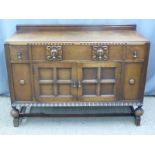 An oak sideboard with three drawers over a two door cabinet W132 x D50 x H96cm