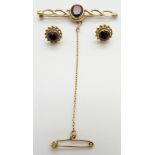 A 9ct gold brooch and earrings set with a garnet to each, 6g