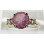 A 14k gold ring set with a pink sapphire flanked by a diamond to each shoulder, 3.2g, size O