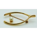 A 9ct gold brooch set with a pearl in a wishbone design, 4.1g